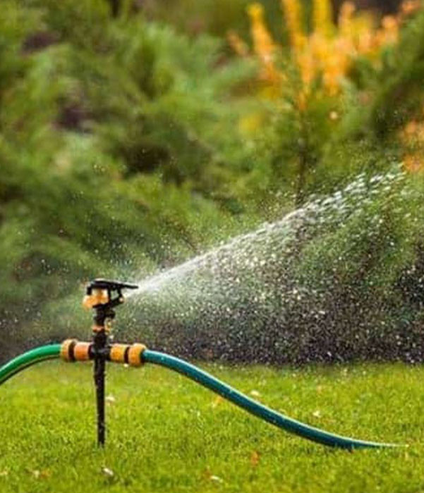 A lawn sprinkler releases a fine mist of water, nourishing the grass and keeping the garden lush and healthy.
