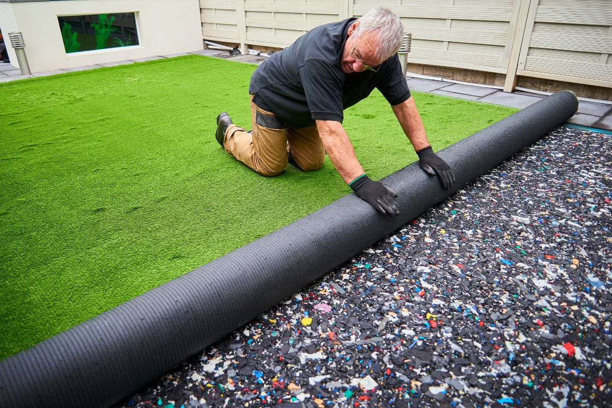 A man reclines on vibrant artificial grass, highlighting the appeal of quality lawn care services.