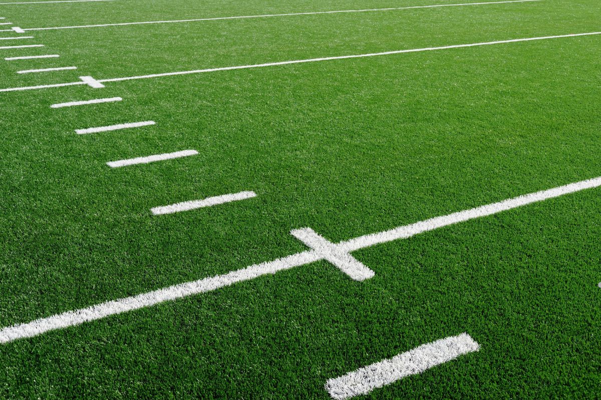 A well-maintained football field featuring vibrant green grass and crisp white lines, showcasing professional lawn care service.