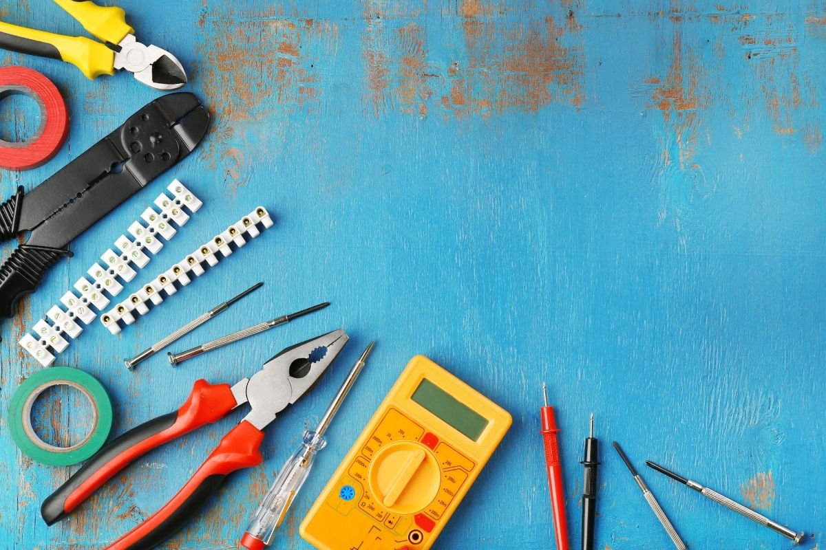 A collection of tools and electrical equipment arranged on a blue background, showcasing various items for repair and maintenance.